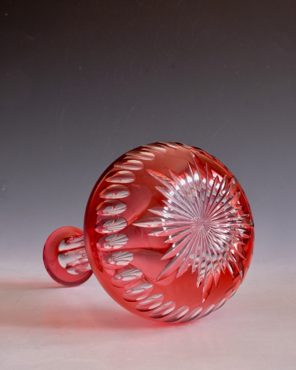 A mid-Victorian ruby overlay cut glass decanter with a matching faceted stopper and slice-cut neck. View VI