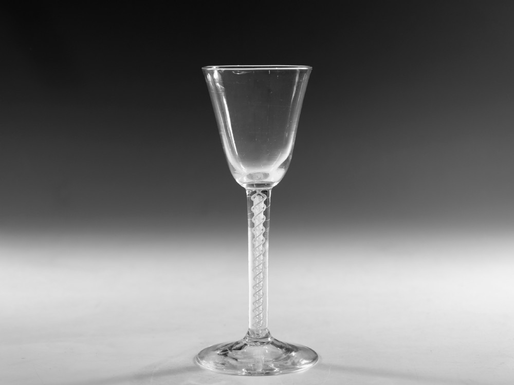 A clear Georgian lead crystal wine glass featuring a bell-shaped bowl, a mixed twist stem, and a circular conical foot.