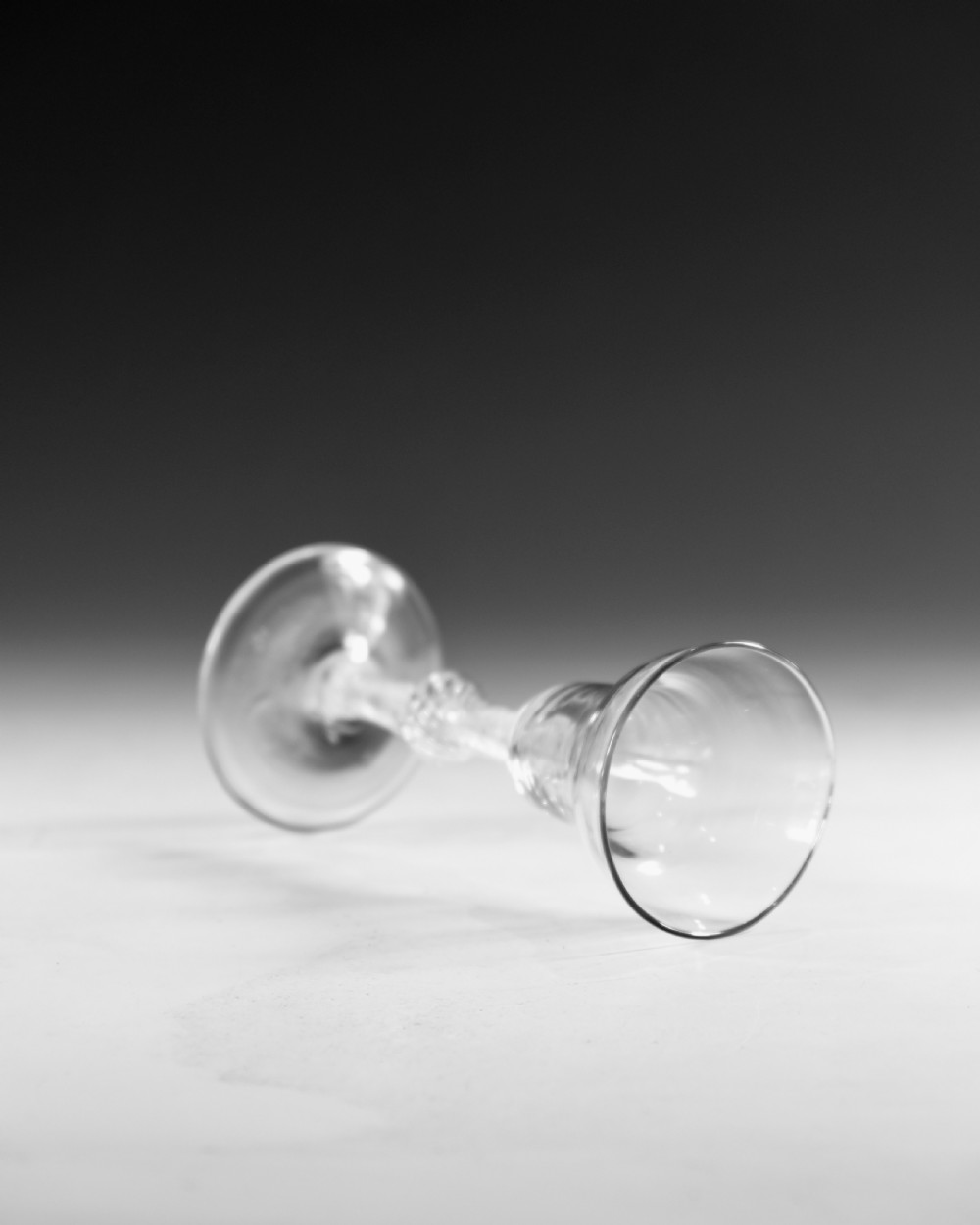 An 18th-century English clear lead glass wine glass featuring a flared bowl, a knopped stem with a multi-spiral air twist pattern, and a wide circular foot. View V