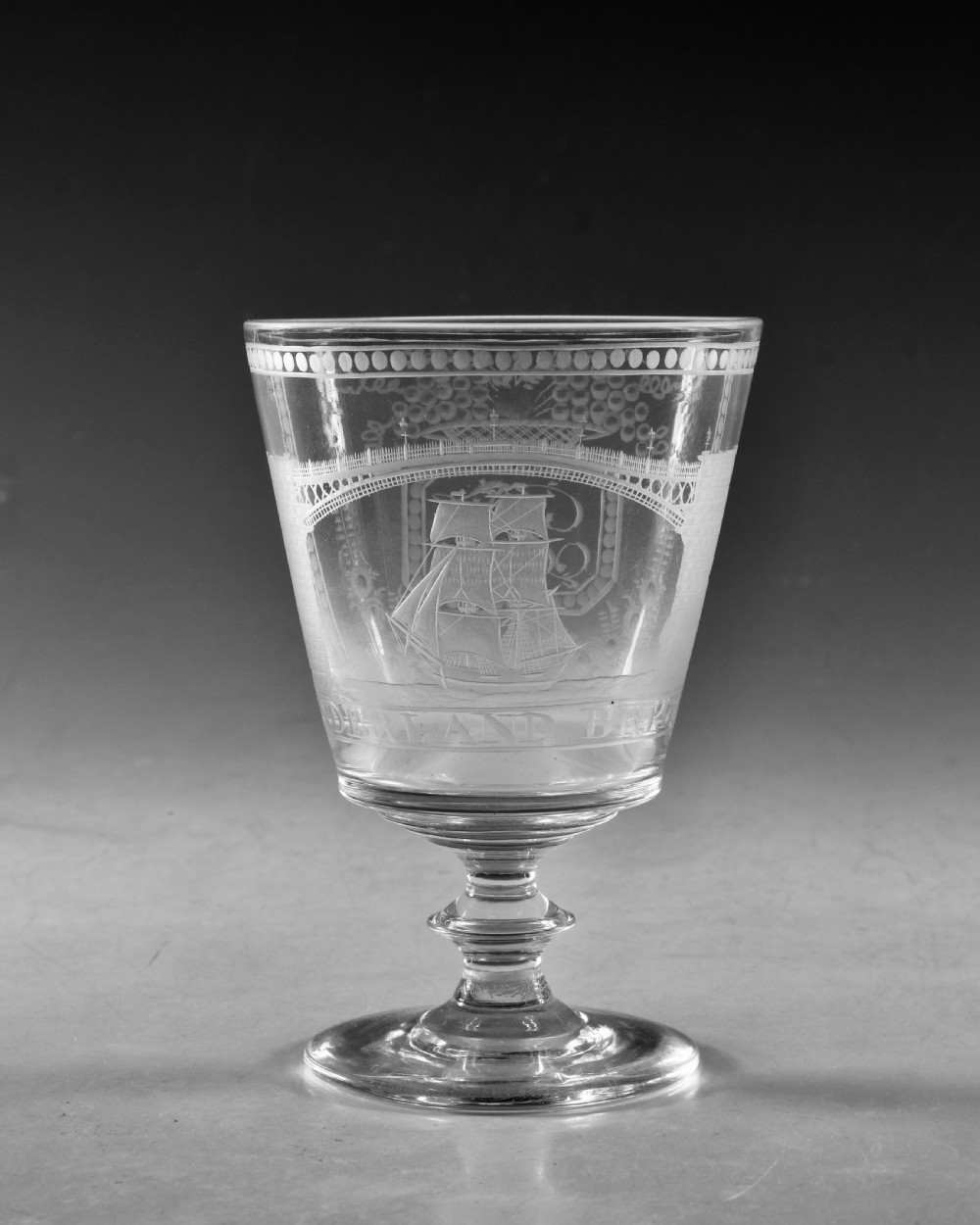 An antique clear glass rummer featuring detailed wheel engraving of a sailing ship beneath the Wearmouth Sunderland Bridge, supported by a knopped stem and circular foot. View II