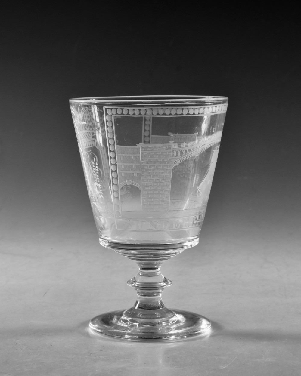 An antique clear glass rummer featuring detailed wheel engraving of a sailing ship beneath the Wearmouth Sunderland Bridge, supported by a knopped stem and circular foot. View III