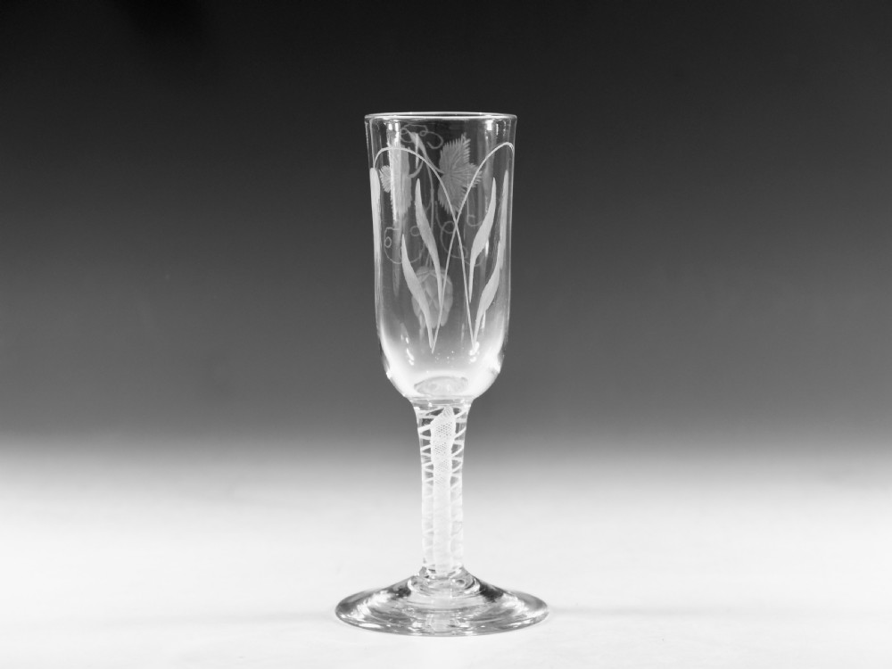 An eighteenth-century lead glass ale flute featuring an engraved hops and barley motif on an elongated bowl, resting upon a double series opaque twist stem and a conical foot.
