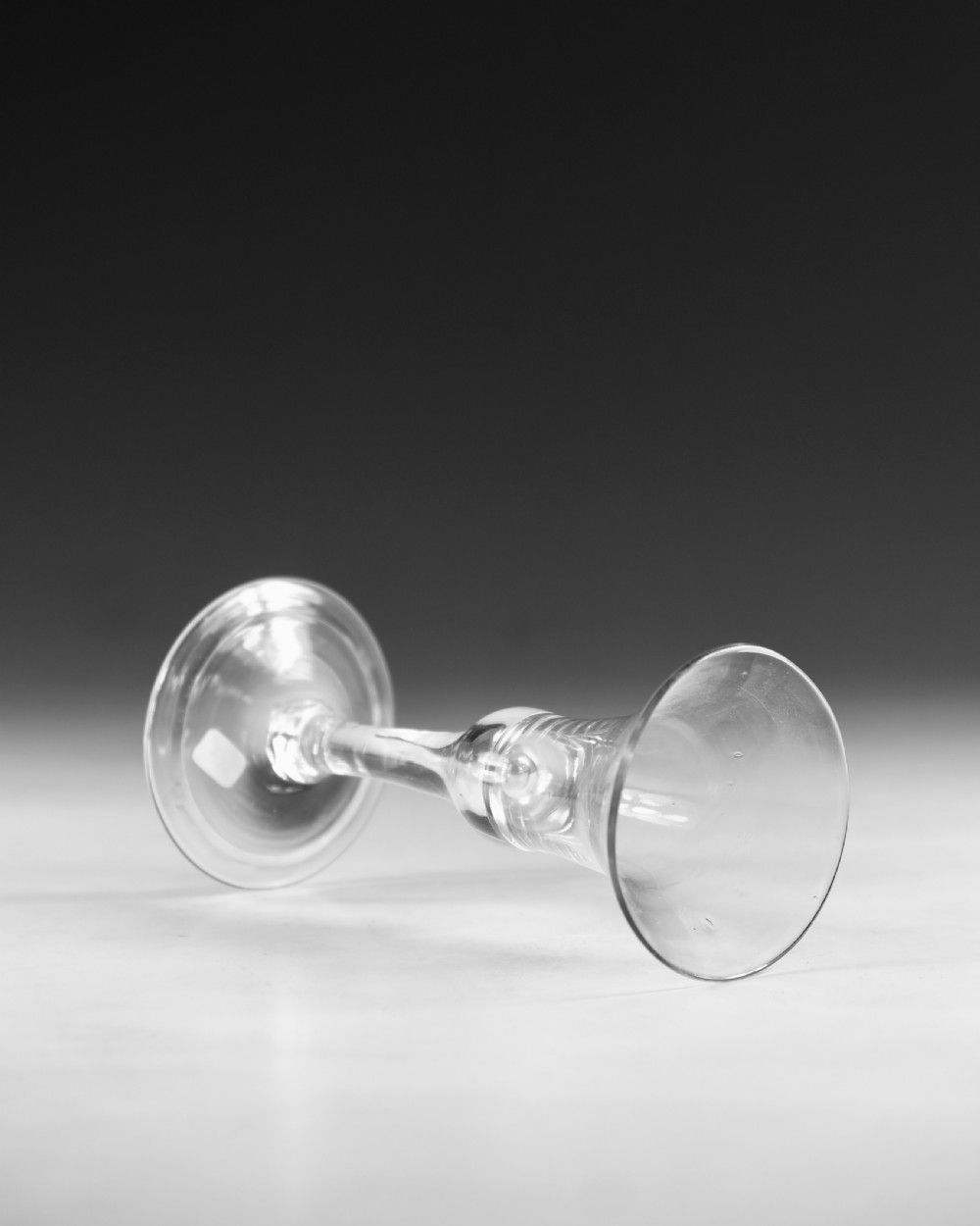 An 18th-century English clear lead glass wine glass featuring a flared bell bowl, a plain stem with a central air tear, and a circular conical foot. View IV