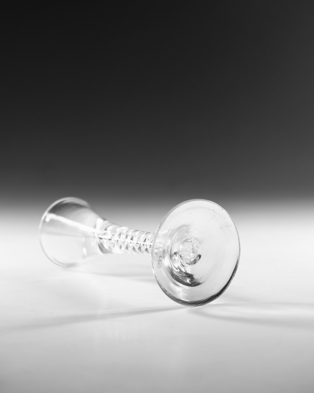 An antique clear lead glass cordial glass featuring a flared funnel bowl, a central mercury air-twist stem, and a wide conical base. View III
