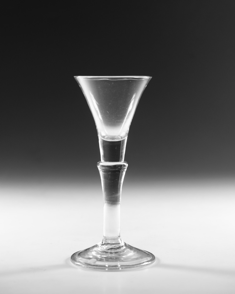 An eighteenth-century clear glass wine glass featuring a flared funnel bowl, a central stem knop, and a conical foot. View II