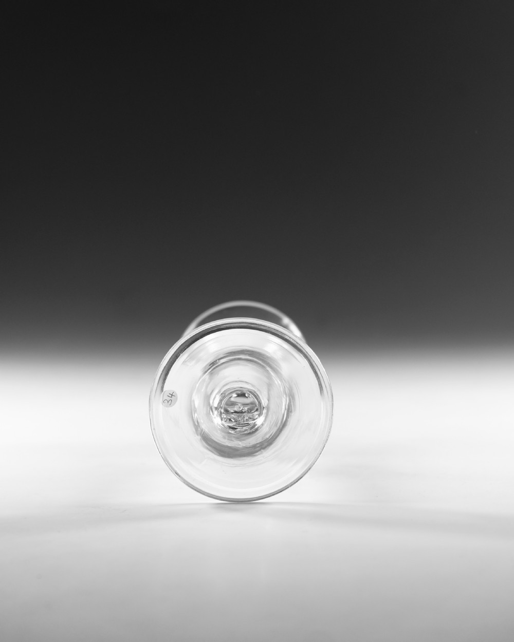 An eighteenth-century clear glass wine glass featuring a flared funnel bowl, a central stem knop, and a conical foot. View V