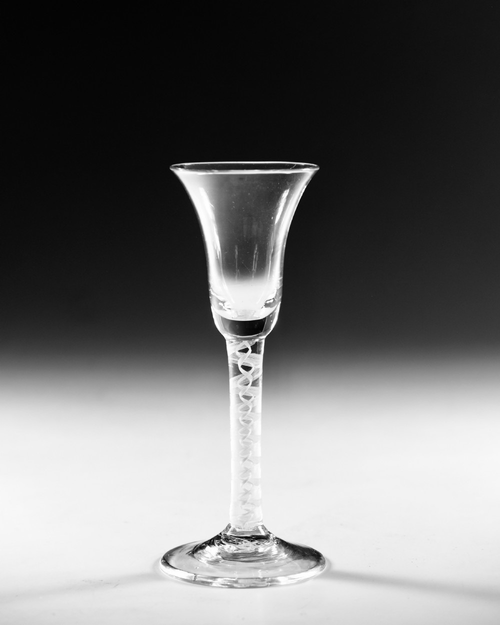 A Georgian clear glass wine goblet with a flared bell bowl and an opaque white spiral twist stem on a circular conical foot. View II