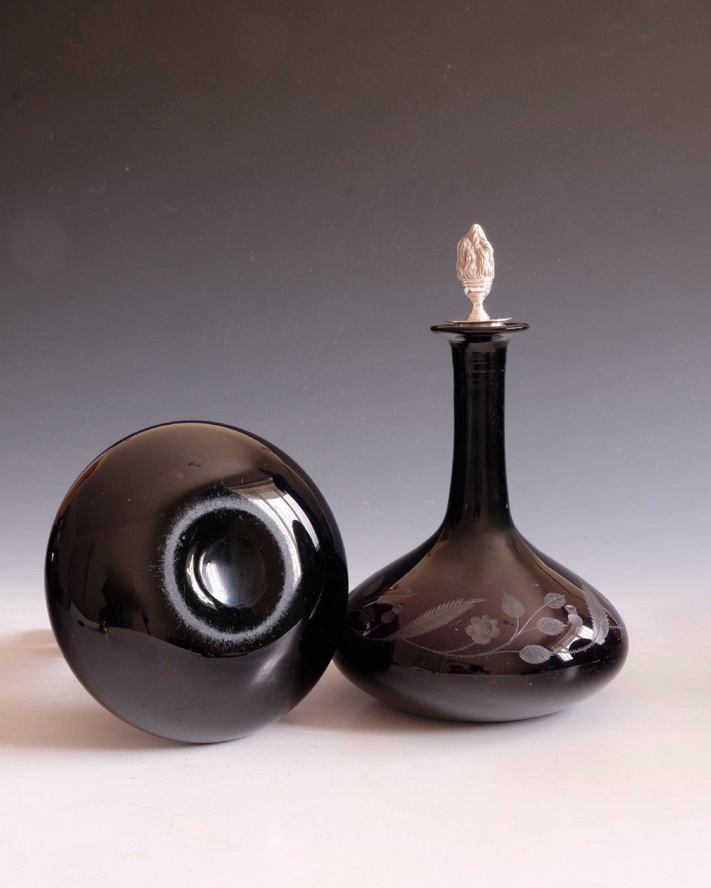 A pair of dark amethyst glass decanters featuring wheel-engraved botanical motifs and topped with silver flame-shaped stoppers. View VI