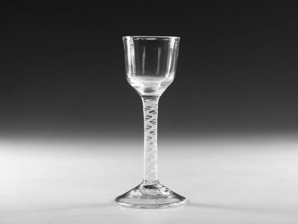 An 18th-century clear glass wine glass featuring an internal white opaque twist stem and a wide conical foot.
