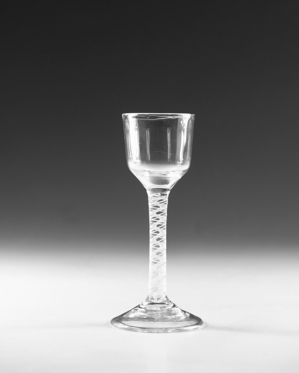 An 18th-century clear glass wine glass featuring an internal white opaque twist stem and a wide conical foot. View II