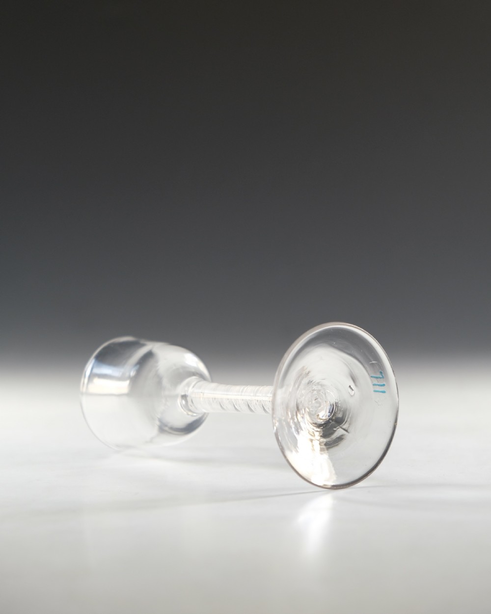 An 18th-century clear glass wine glass featuring an internal white opaque twist stem and a wide conical foot. View III