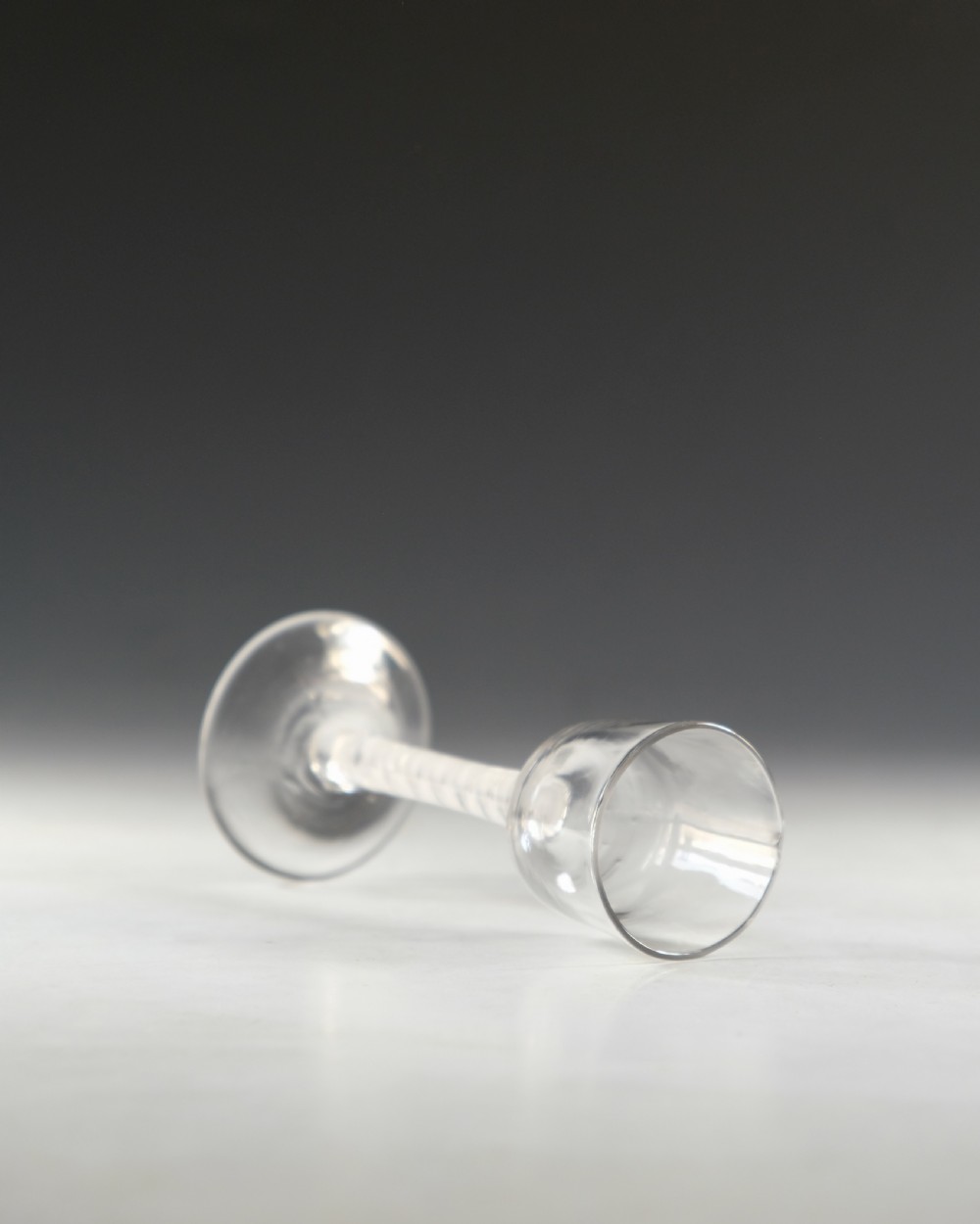 An 18th-century clear glass wine glass featuring an internal white opaque twist stem and a wide conical foot. View IV