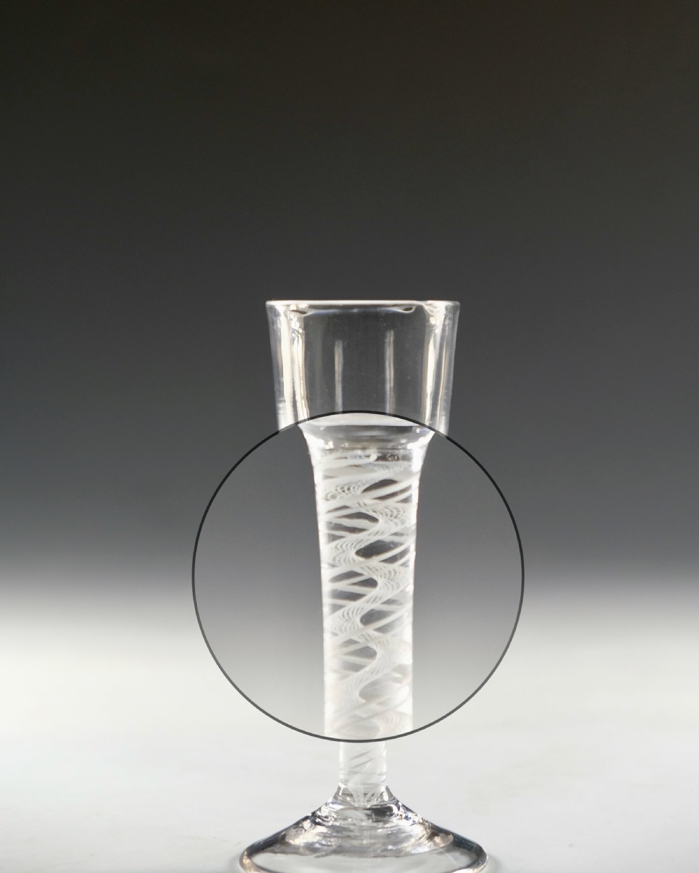 An 18th-century clear glass wine glass featuring an internal white opaque twist stem and a wide conical foot. View V