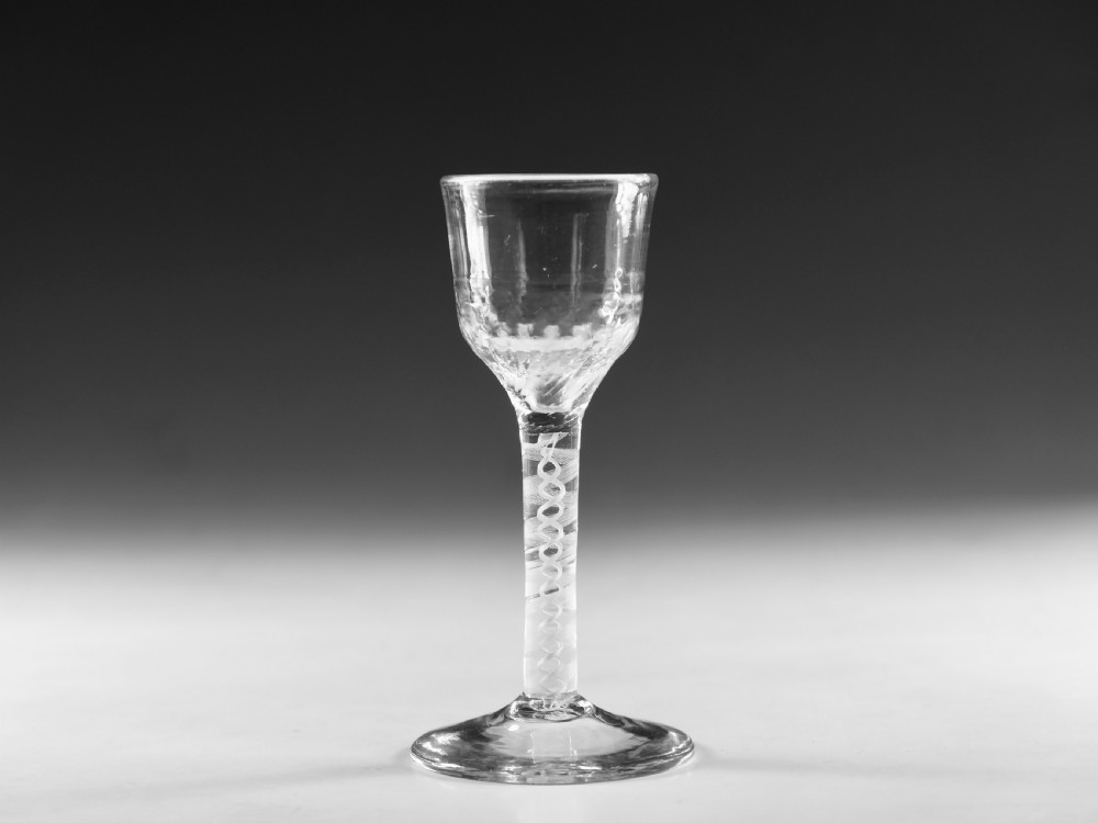 An eighteenth-century clear lead glass wine glass featuring an internal opaque white spiral twist within the stem and a conical foot.