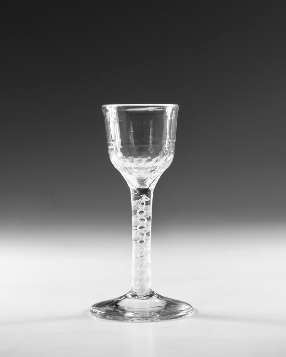 An eighteenth-century clear lead glass wine glass featuring an internal opaque white spiral twist within the stem and a conical foot. View II