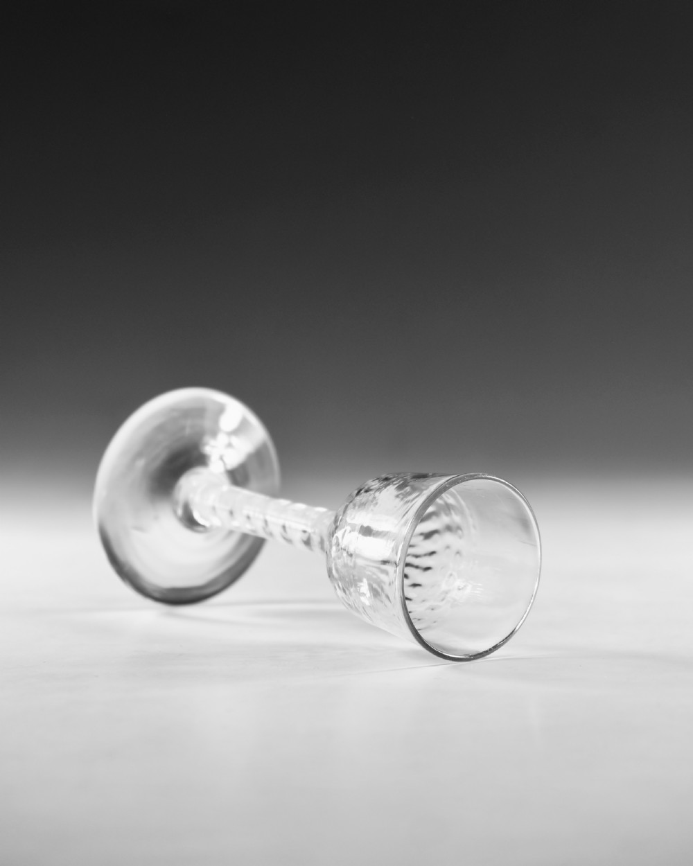 An eighteenth-century clear lead glass wine glass featuring an internal opaque white spiral twist within the stem and a conical foot. View V