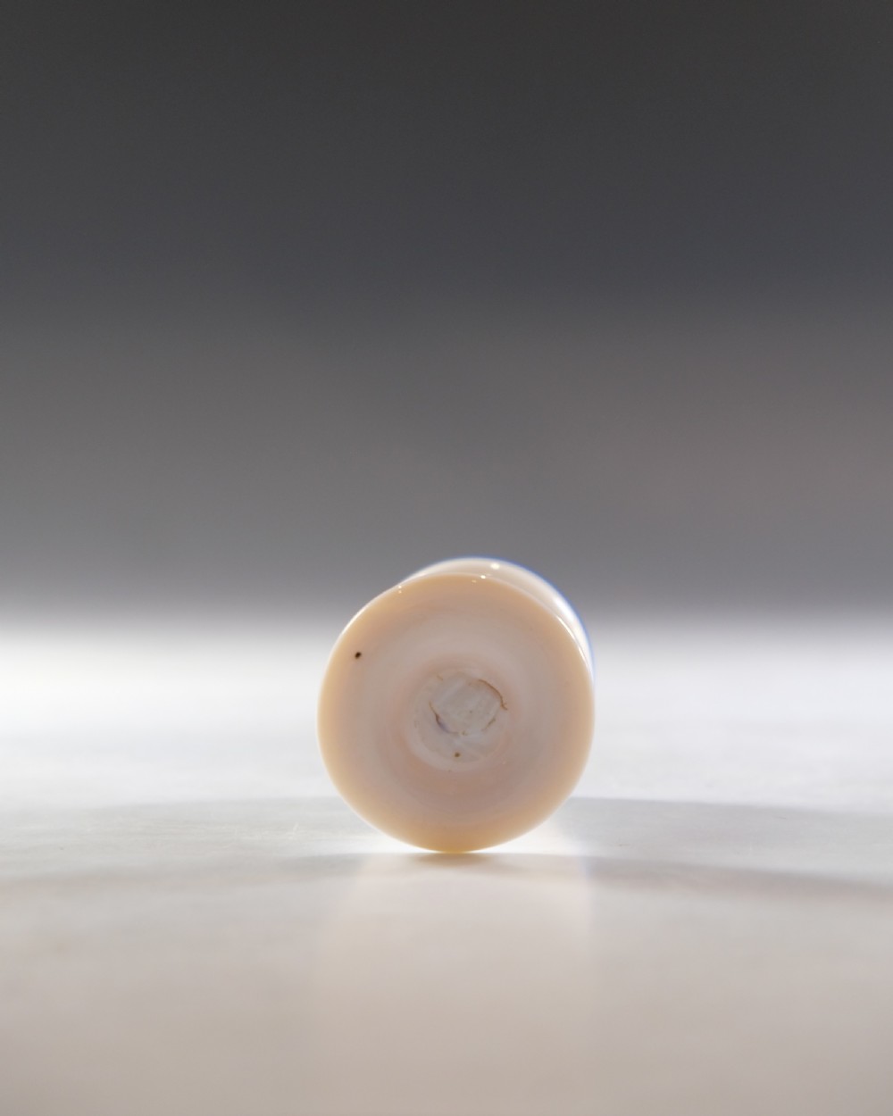 An opaque white glass egg cup featuring a cobalt blue rim on a narrow pedestal stem and flared circular base. View V