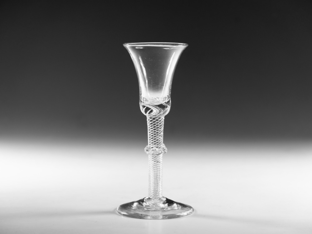 An 18th-century clear glass wine vessel featuring a flared bell bowl, an intricate air-twist stem with a central knop, and a flat conical base.