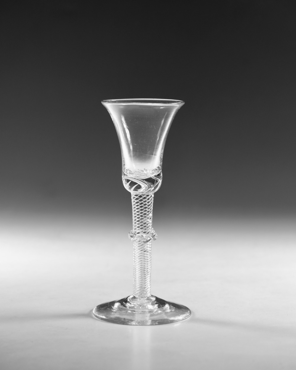 An 18th-century clear glass wine vessel featuring a flared bell bowl, an intricate air-twist stem with a central knop, and a flat conical base. View II
