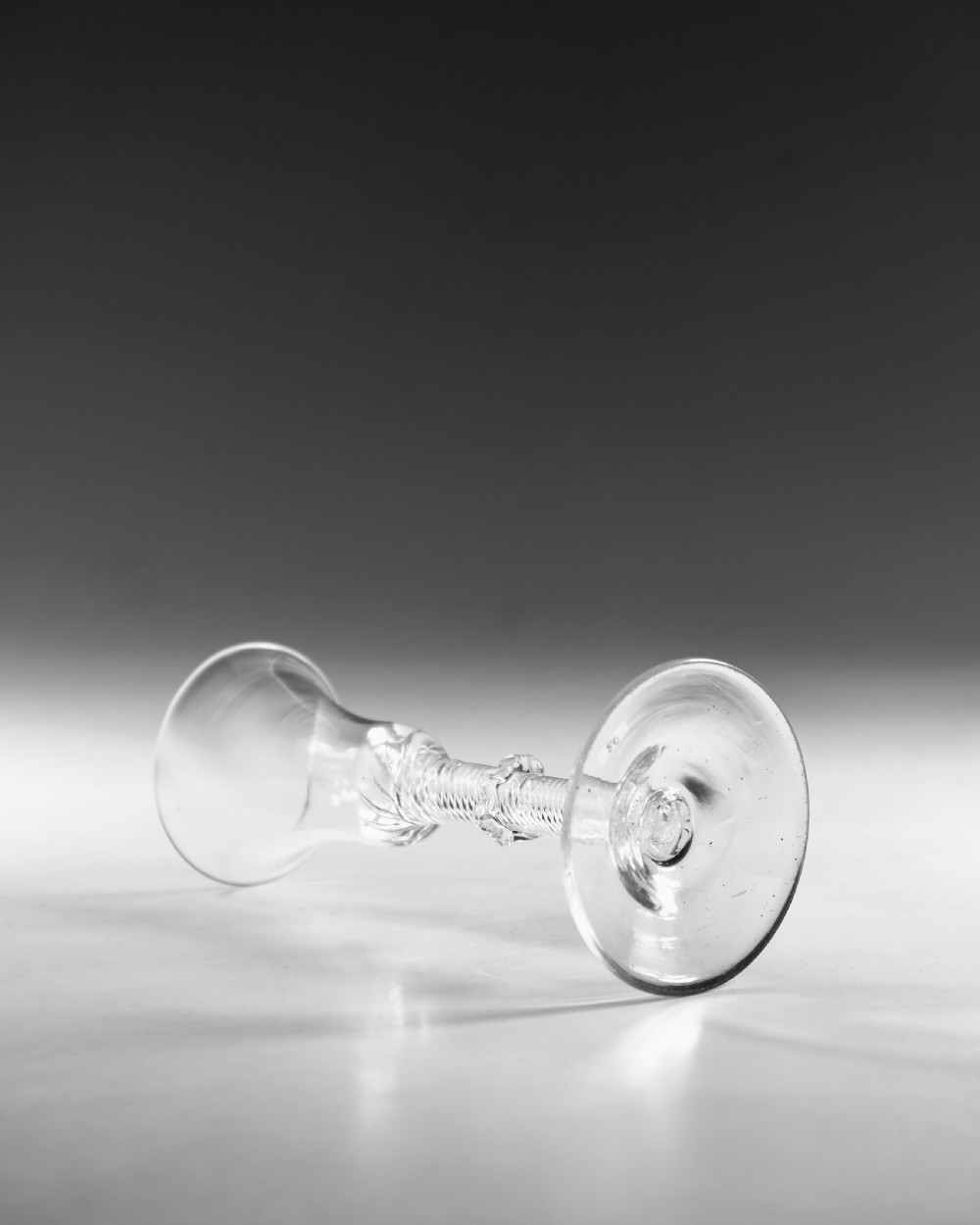 An 18th-century clear glass wine vessel featuring a flared bell bowl, an intricate air-twist stem with a central knop, and a flat conical base. View IV