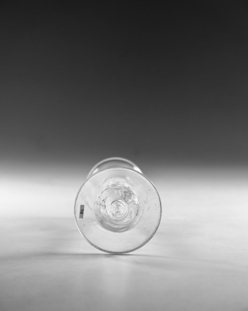 An 18th-century clear glass wine vessel featuring a flared bell bowl, an intricate air-twist stem with a central knop, and a flat conical base. View VI