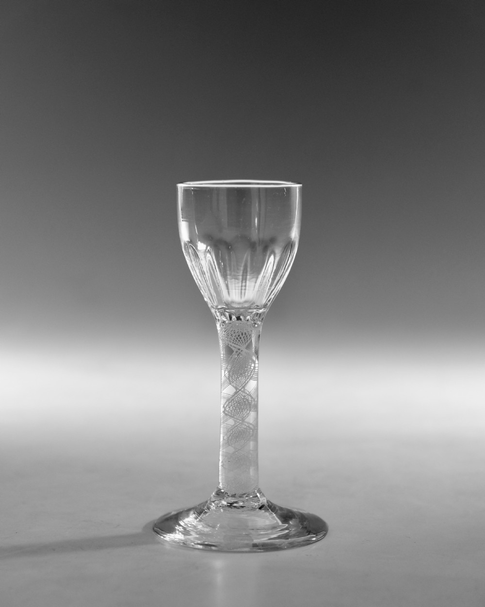 An 18th-century clear glass wine vessel featuring a rounded fluted bowl, an opaque white twist stem, and a conical foot. View II