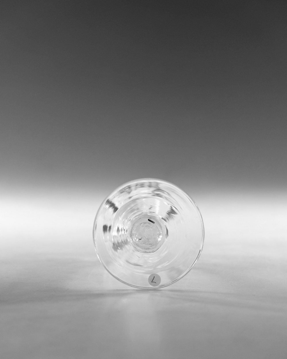 An 18th-century clear glass wine vessel featuring a rounded fluted bowl, an opaque white twist stem, and a conical foot. View VII