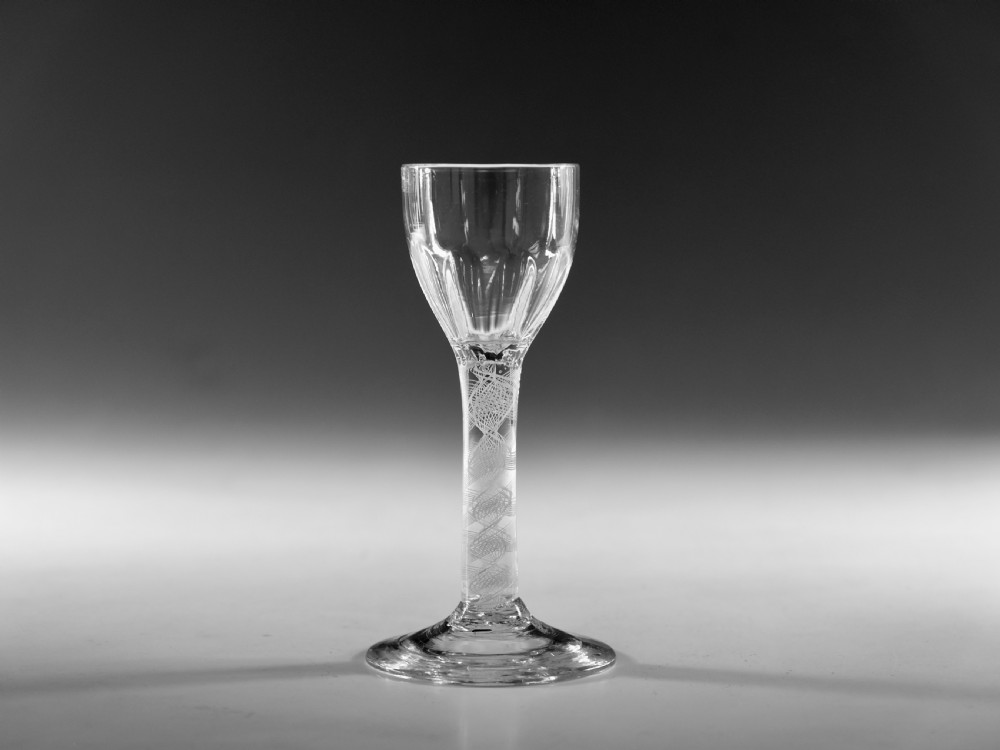 An 18th-century clear glass wine vessel featuring a rounded fluted bowl, an opaque white twist stem, and a conical foot. View VIII