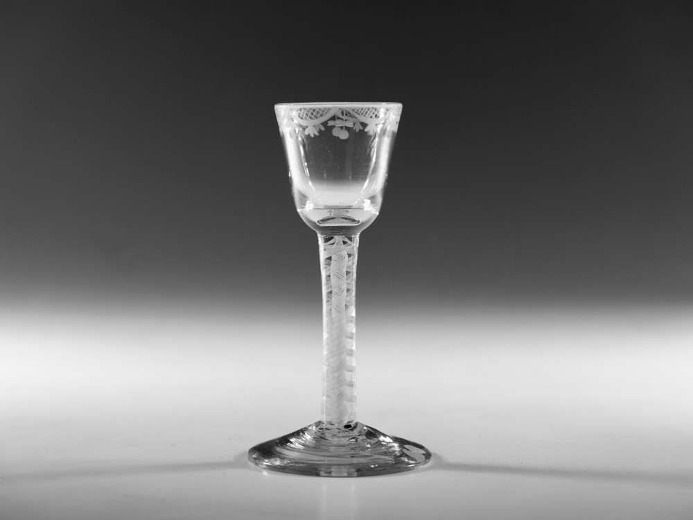 An 18th-century Georgian clear lead glass wine glass featuring an engraved bowl rim, an opaque twist stem, and a circular conical foot.
