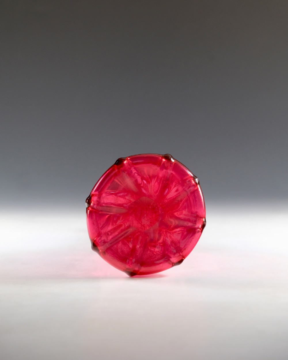 An antique English cranberry red glass serving bottle with a spiralled neck and a fluted lobed body. View V