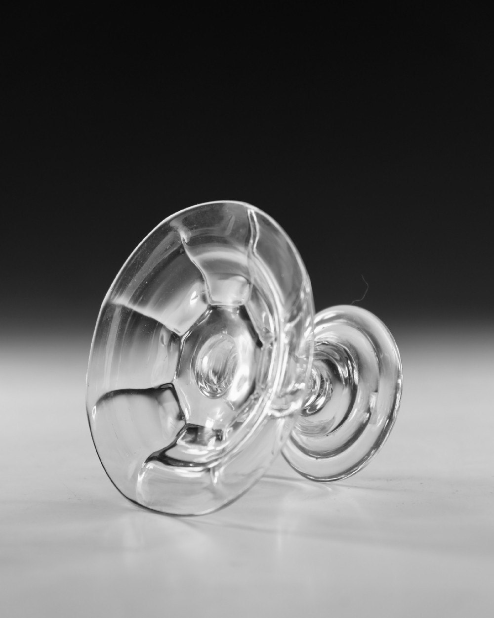 An eighteenth-century Georgian clear lead glass patch stand featuring a shallow rimmed top, a multi-knopped baluster stem, and a circular folded foot. View IV