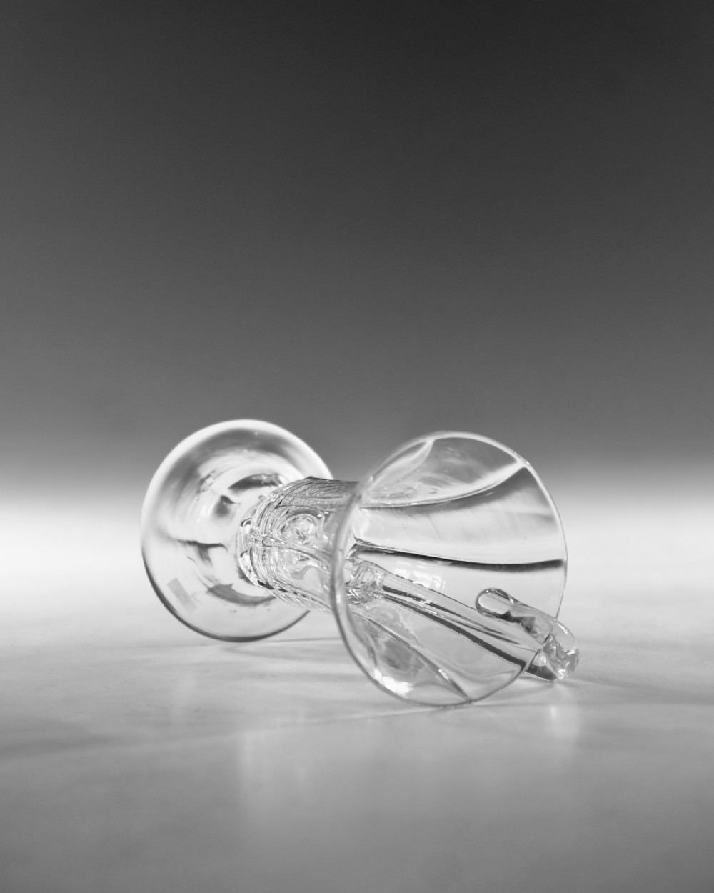 An 18th-century clear glass jelly vessel featuring a fluted bell-shaped bowl, a single side handle, a knopped stem element, and a circular foot. View V