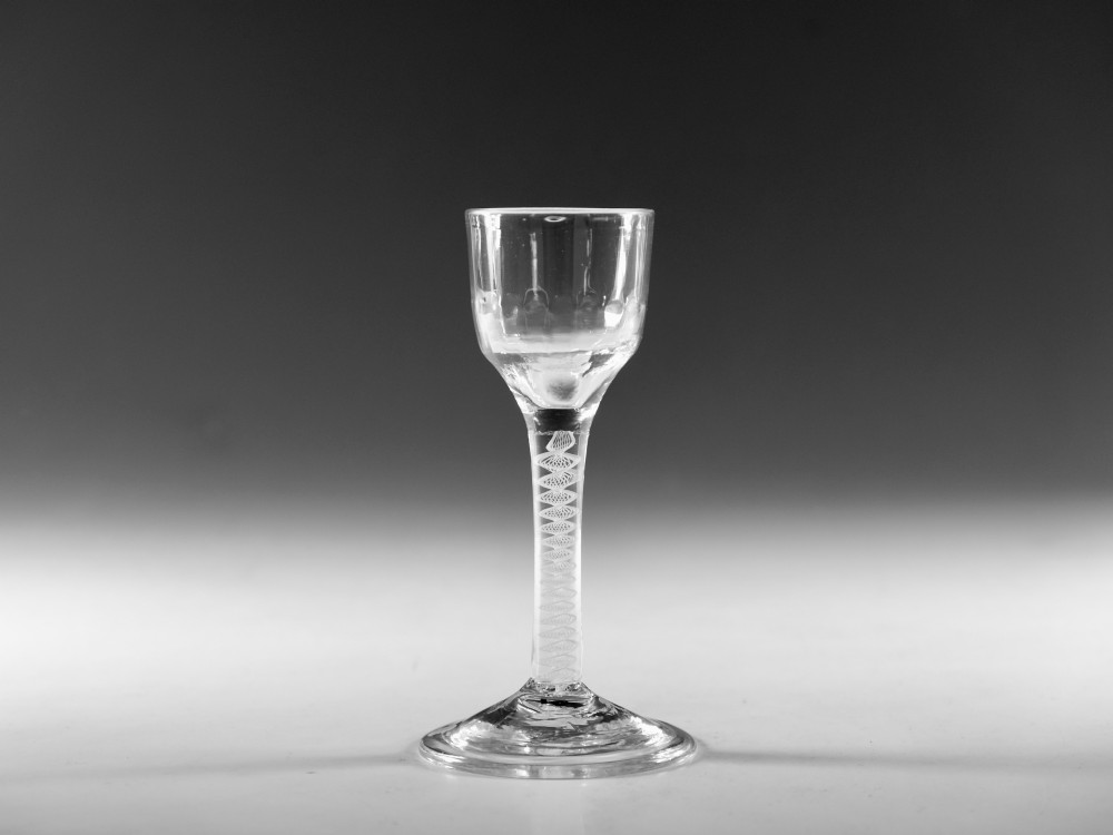 An eighteenth-century clear glass wine goblet featuring a rounded funnel bowl, a internal spiral twist stem, and a wide conical foot.