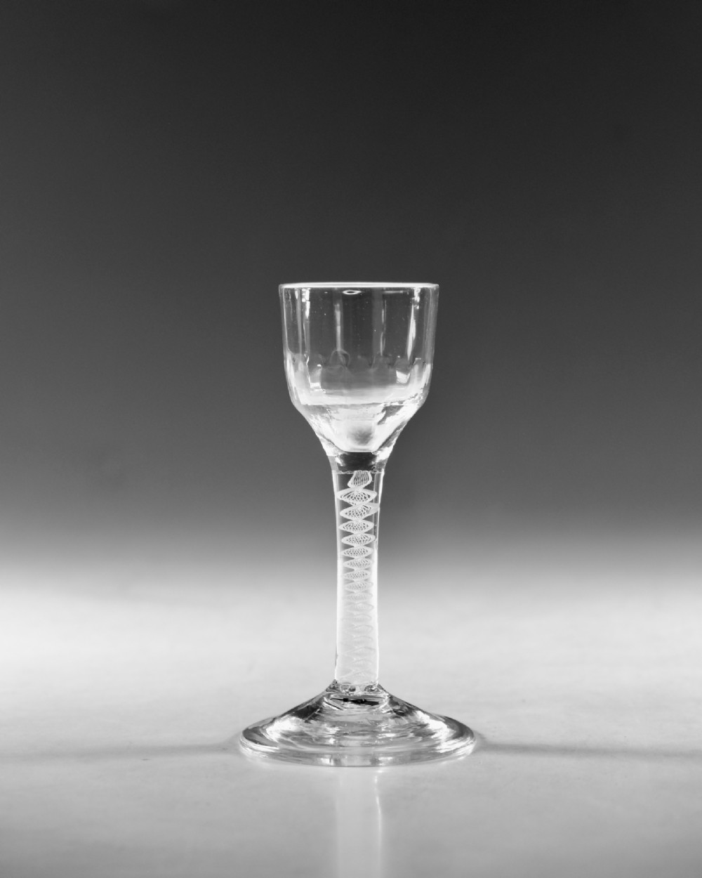 An eighteenth-century clear glass wine goblet featuring a rounded funnel bowl, a internal spiral twist stem, and a wide conical foot. View II