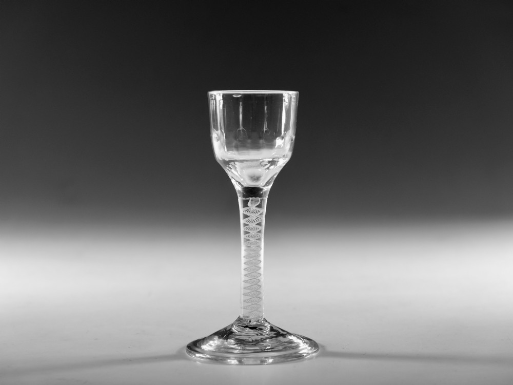 An eighteenth-century clear glass wine goblet featuring a rounded funnel bowl, a internal spiral twist stem, and a wide conical foot. View VI