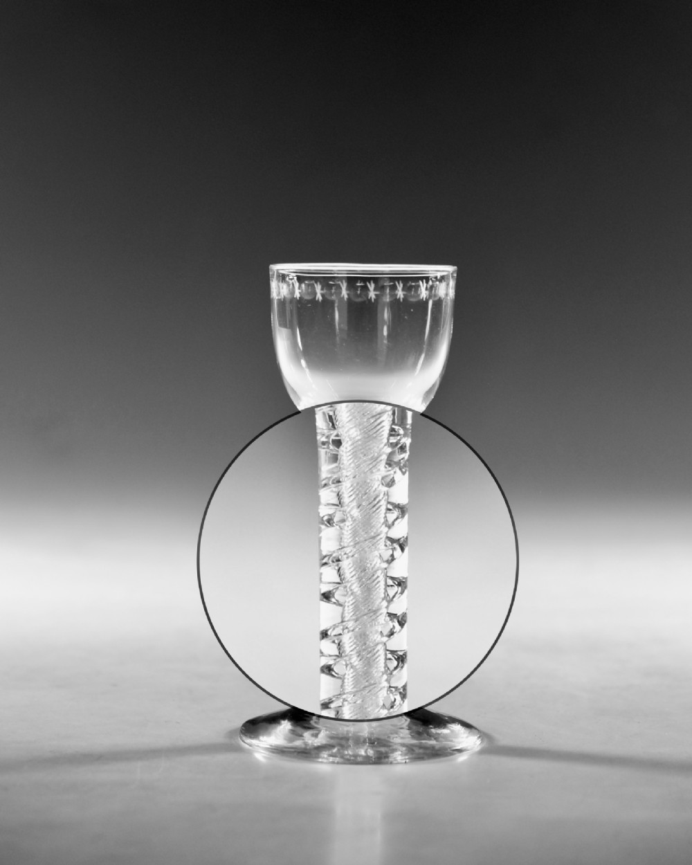 A clear glass wine goblet featuring a wheel-engraved rim pattern, an air twist stem, and a flat conical foot, dating to circa 1755. View III