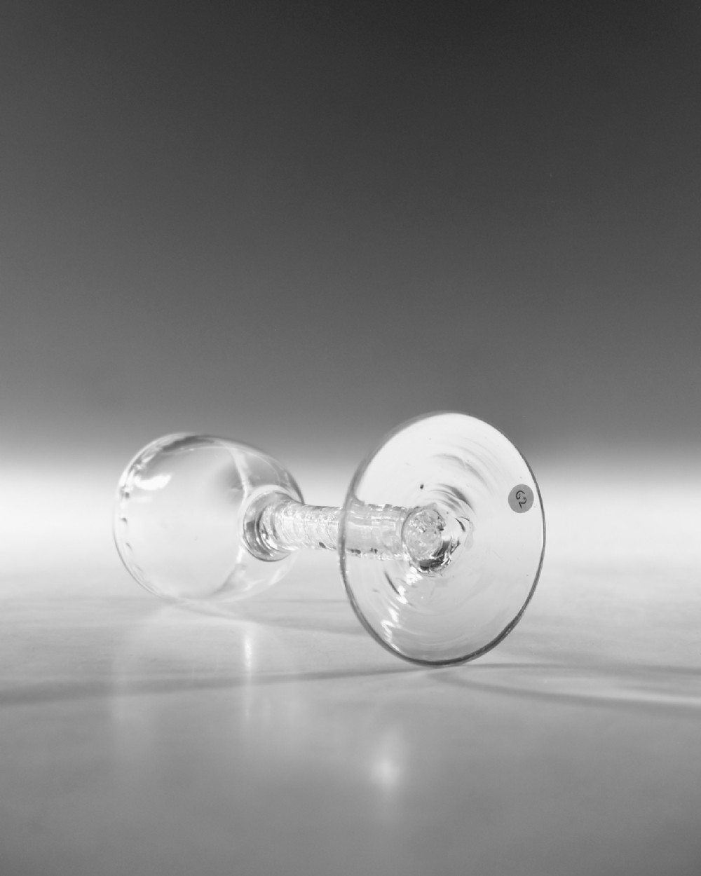 A clear glass wine goblet featuring a wheel-engraved rim pattern, an air twist stem, and a flat conical foot, dating to circa 1755. View IV