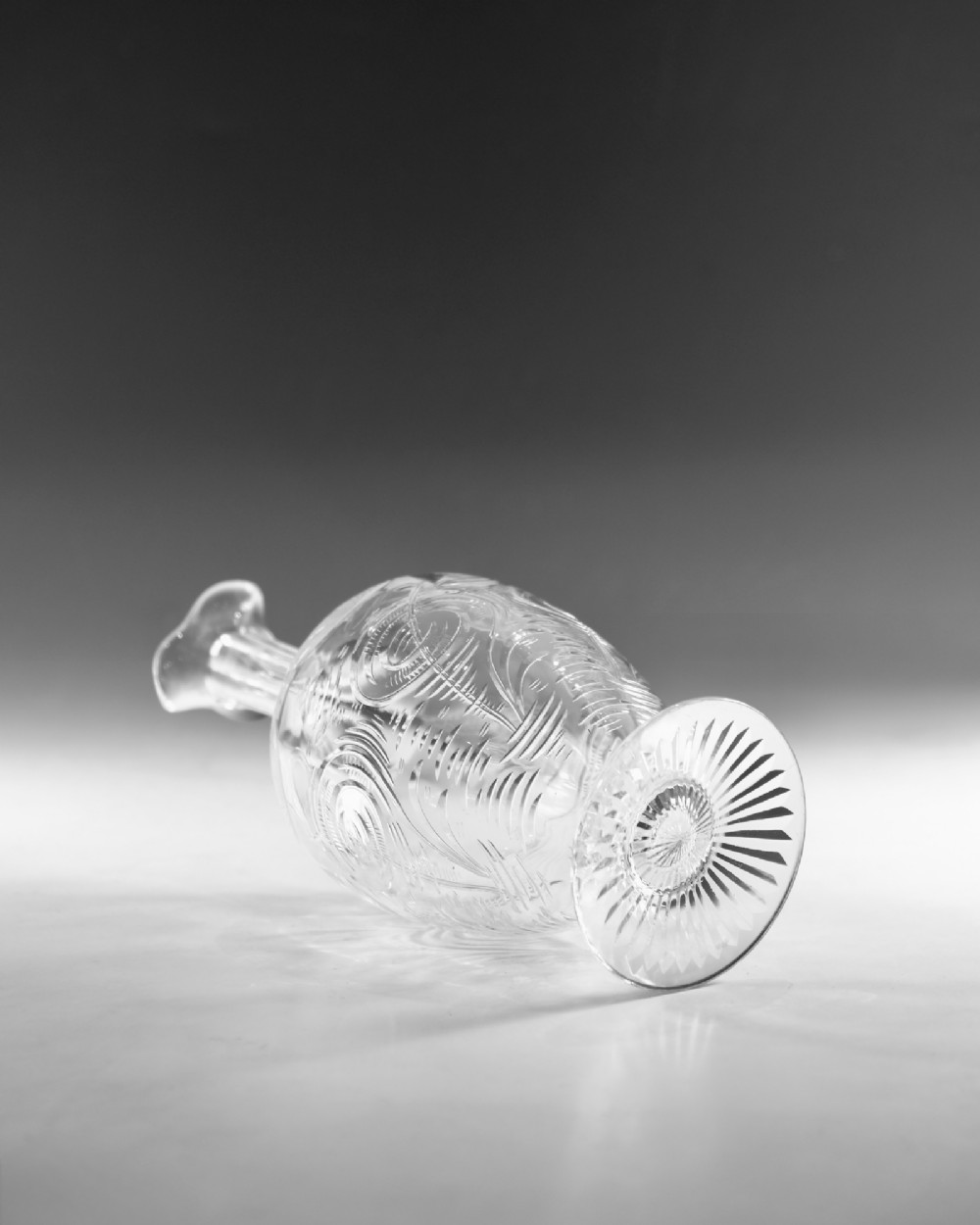 A pair of antique clear glass decanters with intaglio water lily engravings, tall slender necks, and matching glass stoppers. View V
