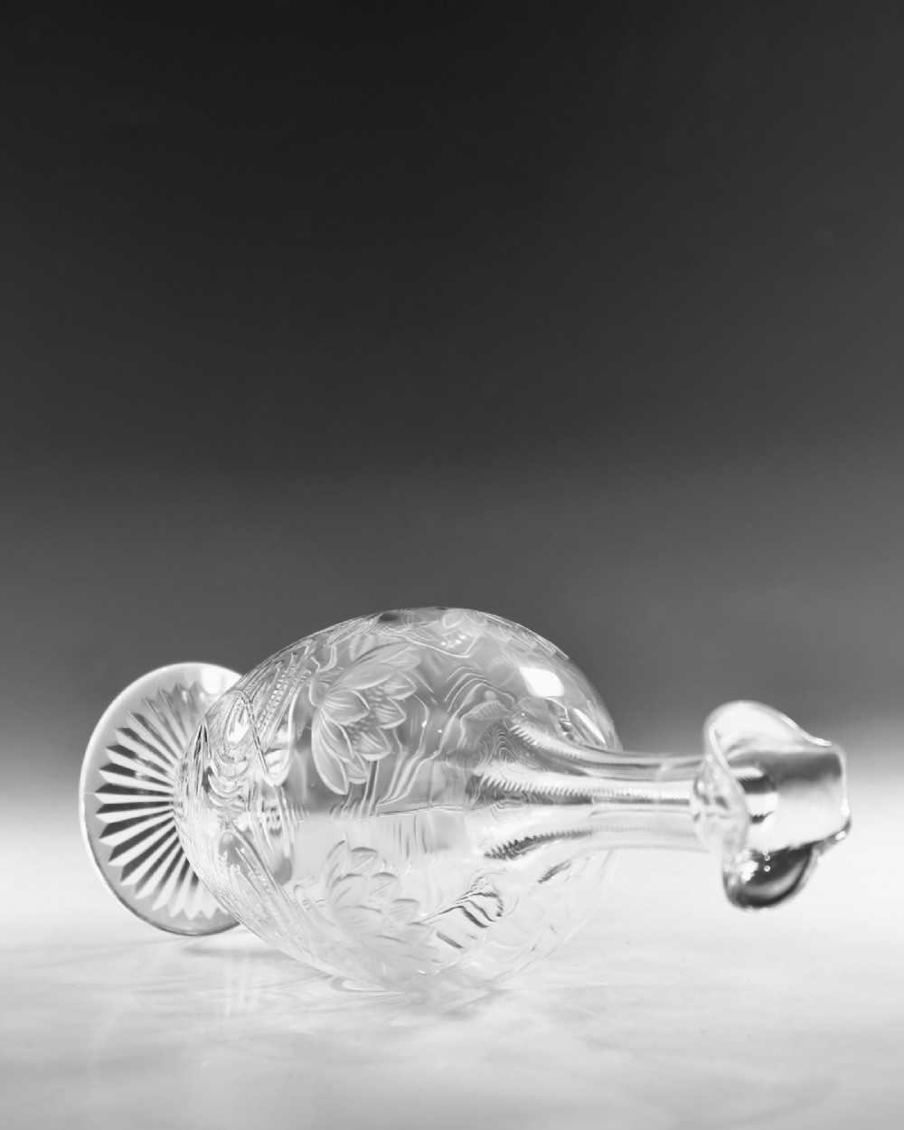 A pair of antique clear glass decanters with intaglio water lily engravings, tall slender necks, and matching glass stoppers. View VI