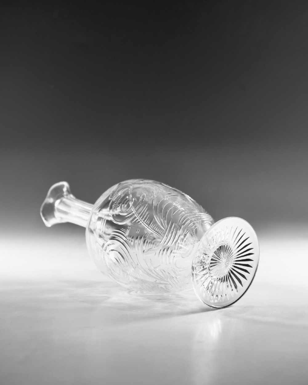 A pair of antique clear glass decanters with intaglio water lily engravings, tall slender necks, and matching glass stoppers. View X