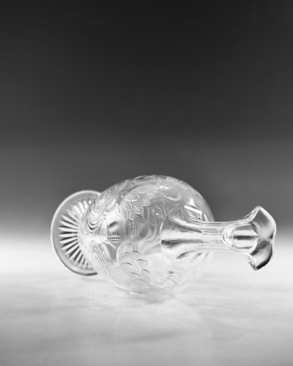 A pair of antique clear glass decanters with intaglio water lily engravings, tall slender necks, and matching glass stoppers. View XI