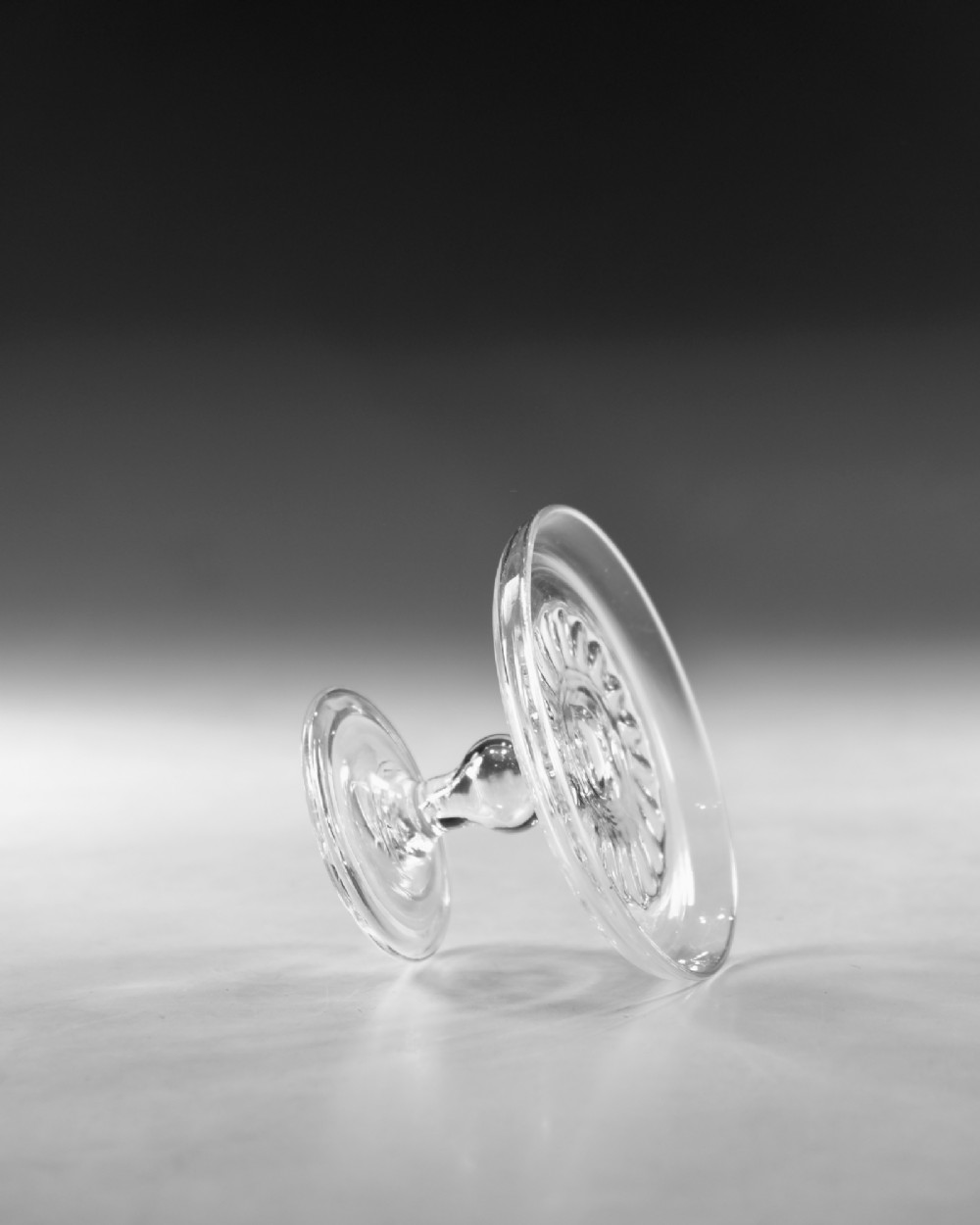 A clear Georgian lead glass patch stand featuring a shallow circular top dish elevated on a baluster stem and a spreading foot. View IV