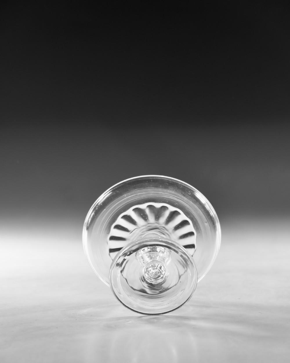 A clear Georgian lead glass patch stand featuring a shallow circular top dish elevated on a baluster stem and a spreading foot. View VI