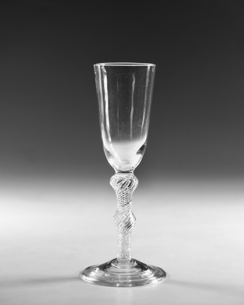 A Georgian clear glass ale flute with a tall bowl, knopped air twist stem, and a flat conical base. View II
