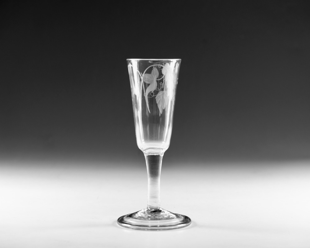 A tall Georgian clear glass ale flute with an engraved hop and barley motif, a straight plain stem, and a flat conical base. View VII