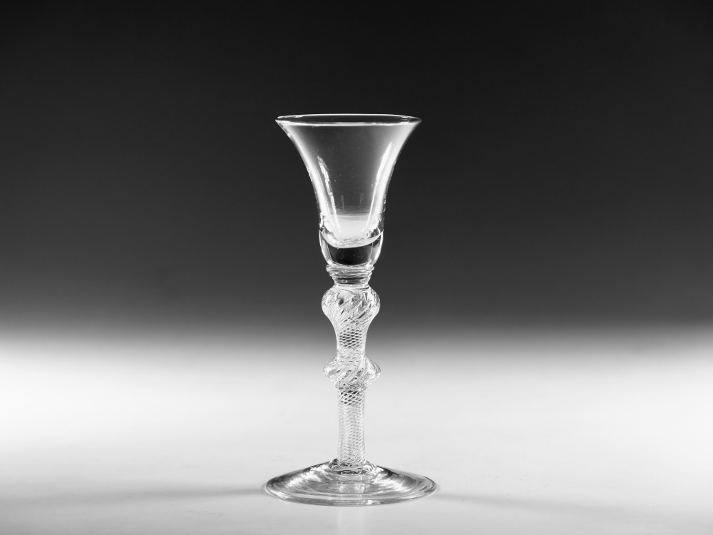 A clear hand-blown Georgian lead crystal wine glass featuring a bell-shaped bowl, a knopped air twist stem, and a broad conical foot.