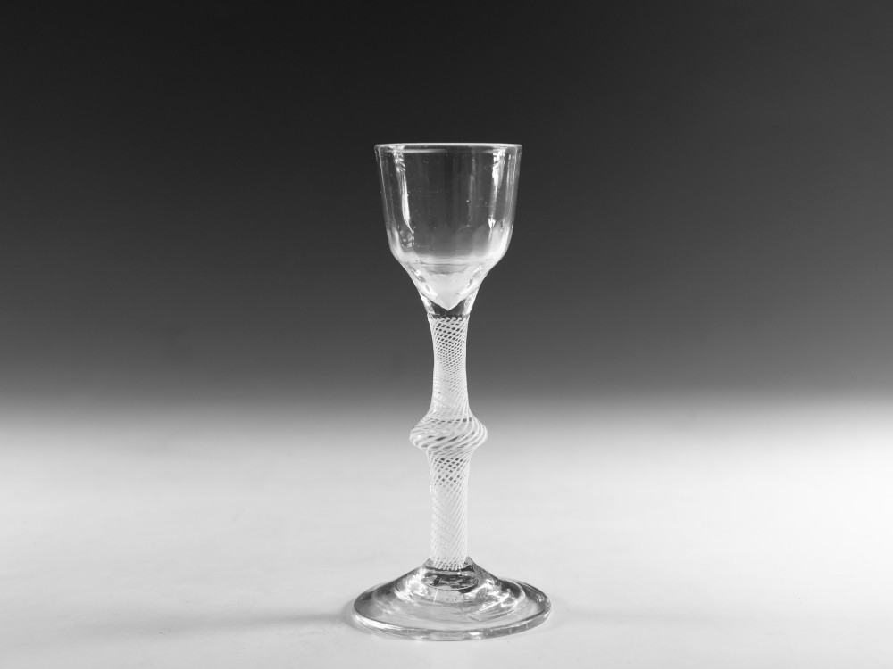 An 18th-century English Georgian clear glass wine glass featuring a funnel bowl and an opaque white twist stem with a central knop.