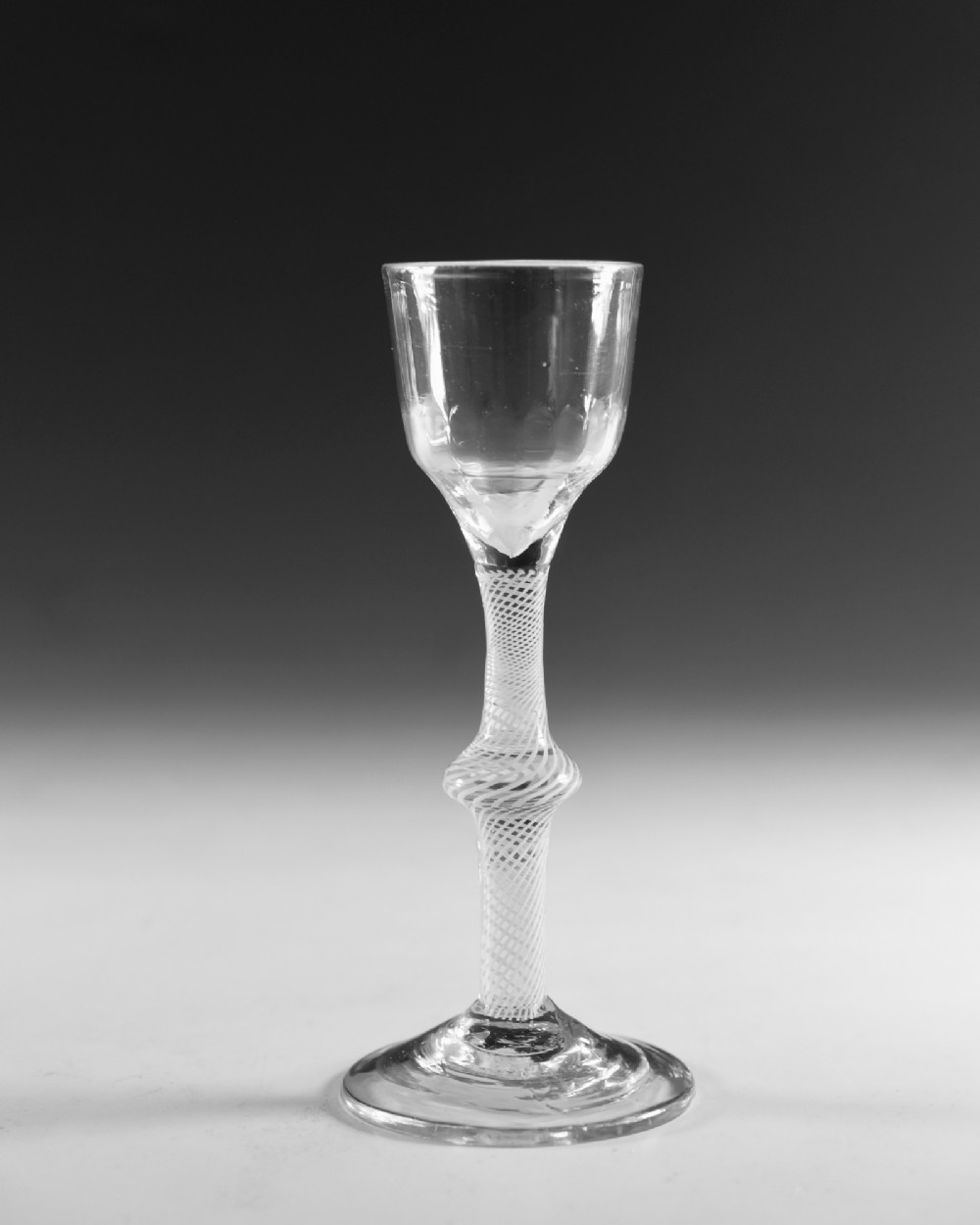 An 18th-century English Georgian clear glass wine glass featuring a funnel bowl and an opaque white twist stem with a central knop. View II