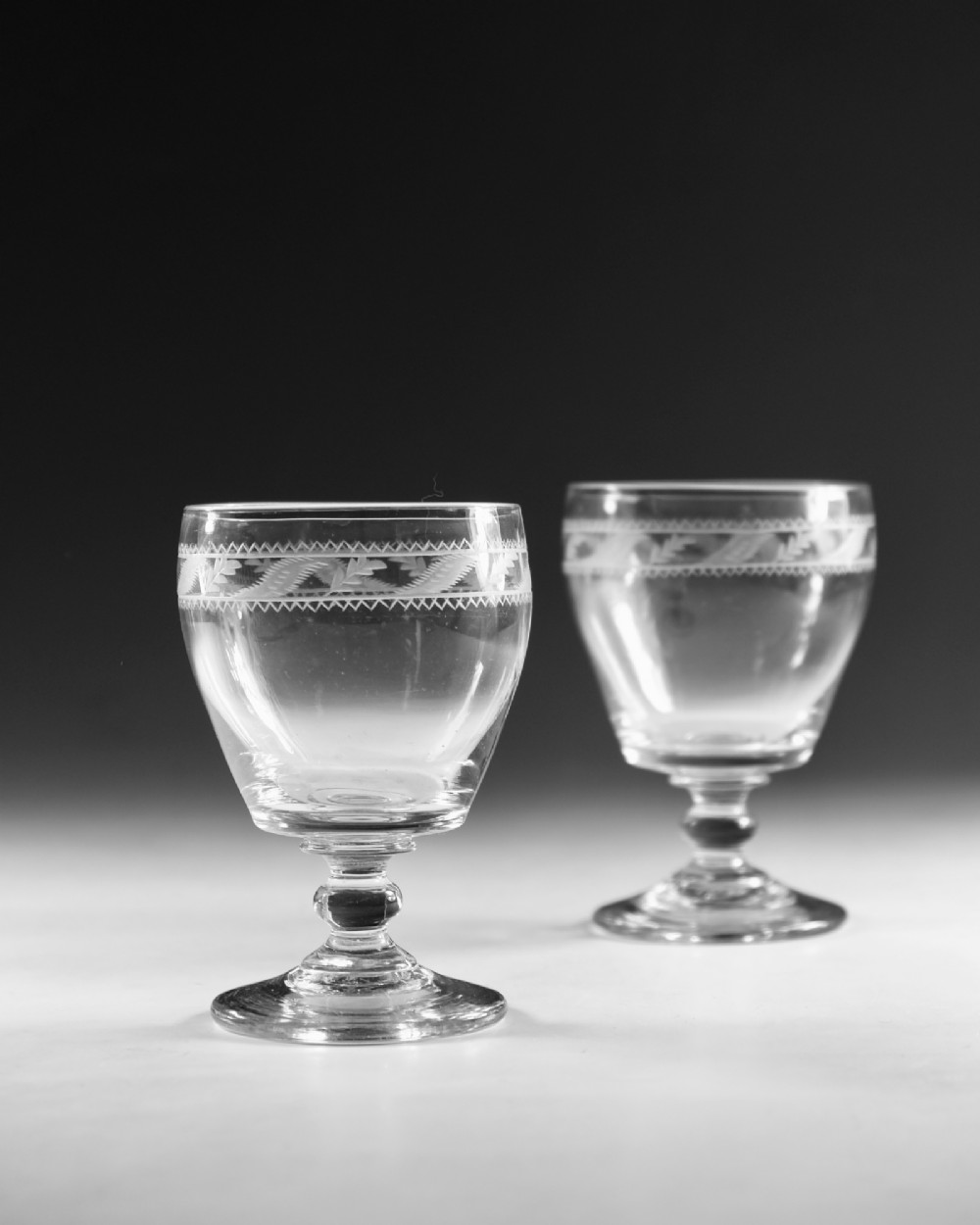 A pair of clear Georgian glass rummers with hand-engraved geometric borders and knopped stems on circular bases. View III