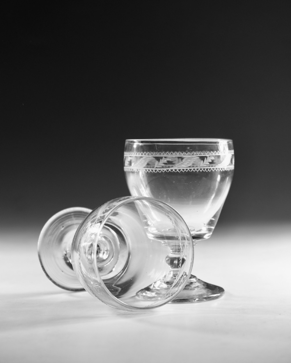 A pair of clear Georgian glass rummers with hand-engraved geometric borders and knopped stems on circular bases. View VI